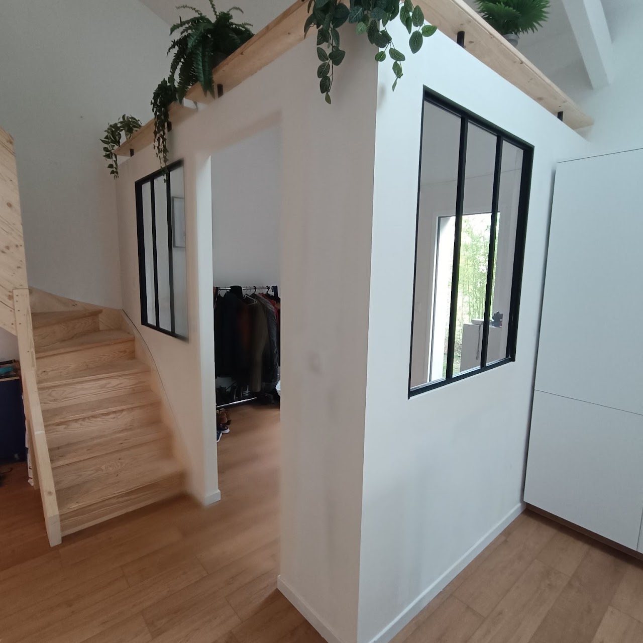 Cloisons en placo avec verrières noires, à côté d’un escalier en bois