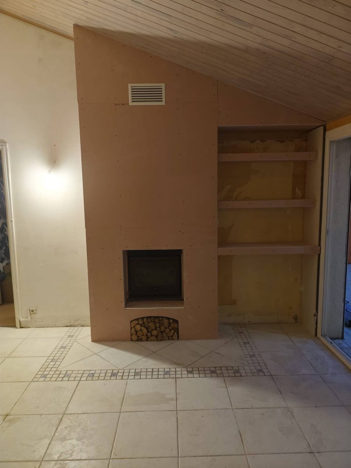 Cheminée habillée de plaques avec niche à bois et étagères intégrées